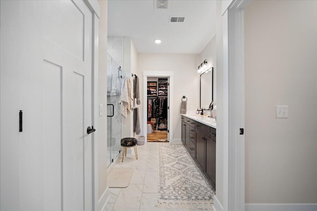 full bathroom with a shower stall, a walk in closet, vanity, marble look tiles, and recessed lighting