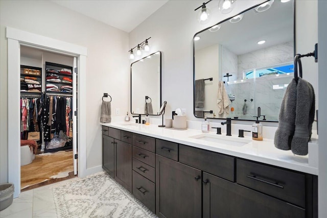 full bathroom with marble look tile flooring, a marble finish shower, double vanity, and a walk in closet