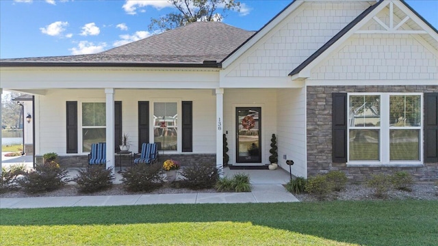 craftsman-style home featuring stone siding, a porch, and a front yard
