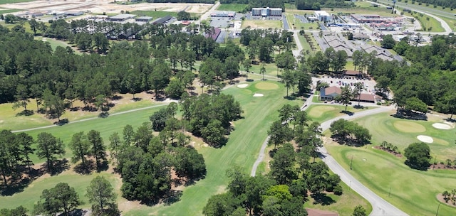 aerial overview of property's location featuring a golf course and a tree filled landscape