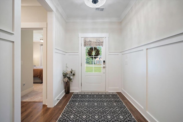 entryway with dark wood finished floors, a decorative wall, and ornamental molding