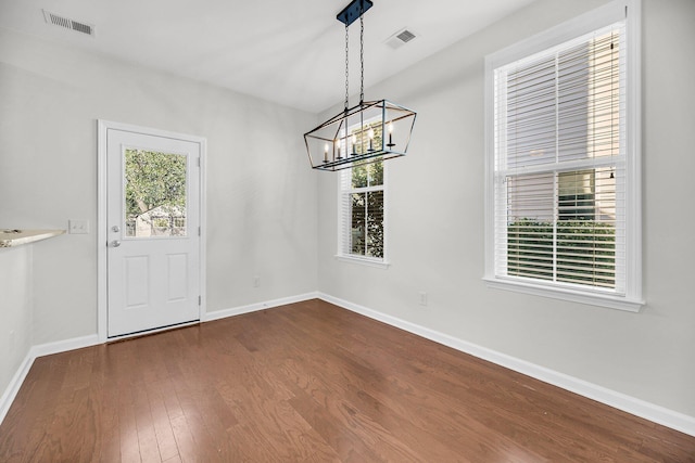 unfurnished dining area featuring a chandelier and dark hardwood / wood-style floors