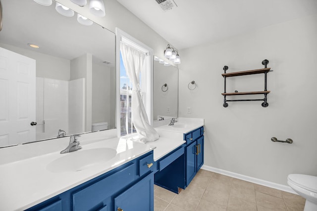 bathroom featuring toilet, vanity, tile patterned flooring, and walk in shower