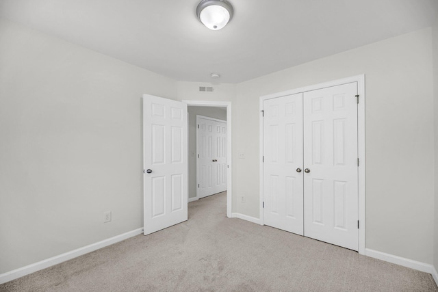 unfurnished bedroom featuring a closet and light carpet