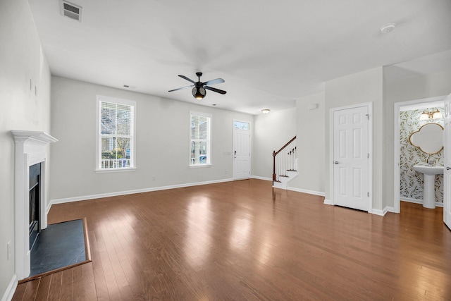 unfurnished living room featuring dark wood-type flooring and ceiling fan