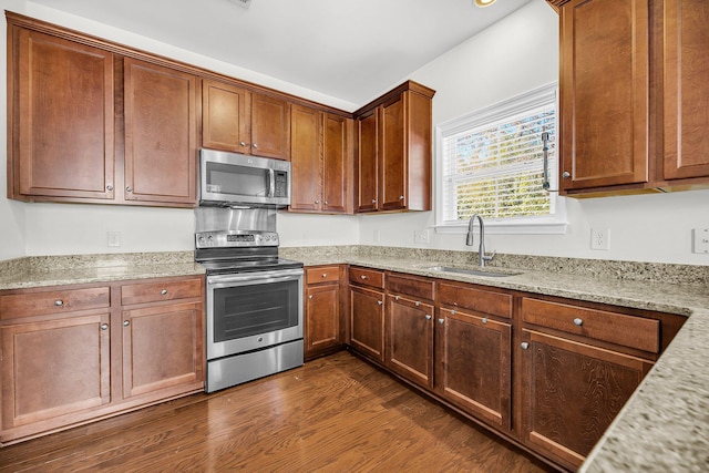 kitchen with light stone counters, stainless steel appliances, dark wood-type flooring, and sink