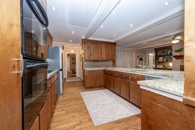 kitchen featuring ornamental molding, sink, light hardwood / wood-style floors, and kitchen peninsula