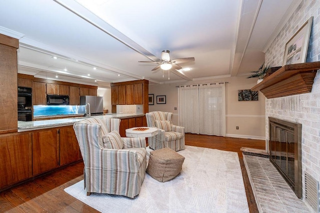 living room featuring ceiling fan, a fireplace, dark hardwood / wood-style floors, and beamed ceiling