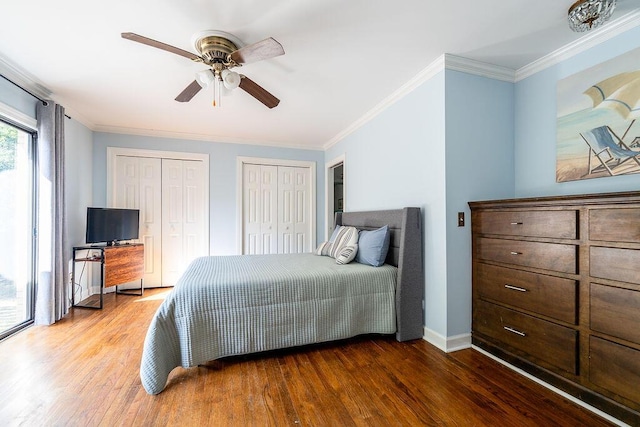 bedroom with two closets, wood-type flooring, ornamental molding, and ceiling fan