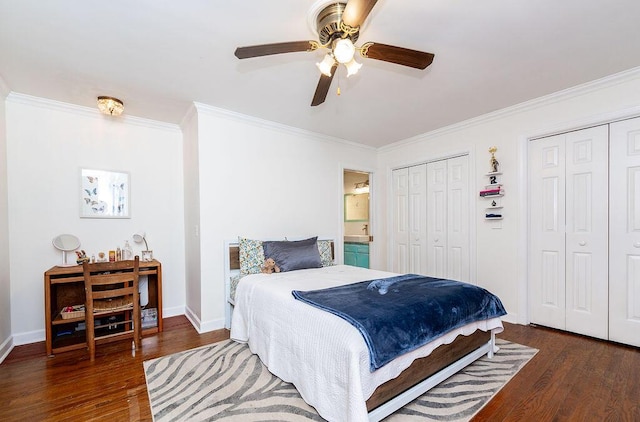 bedroom featuring crown molding, ceiling fan, ensuite bathroom, dark hardwood / wood-style flooring, and multiple closets