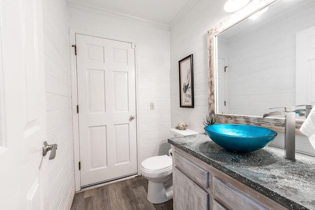 bathroom with wood-type flooring, ornamental molding, vanity, and toilet