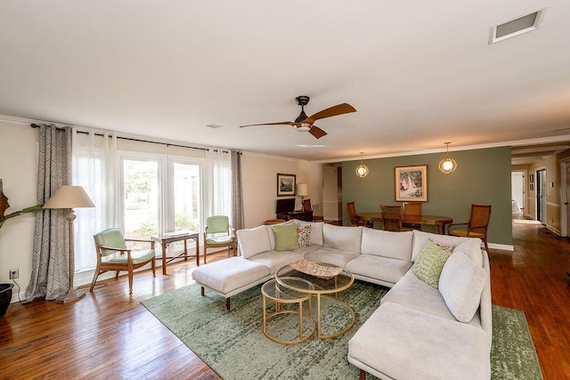 living room featuring crown molding, ceiling fan, and dark wood-type flooring