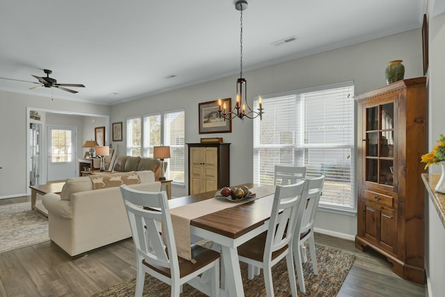 dining room featuring crown molding, dark wood-type flooring, and ceiling fan with notable chandelier