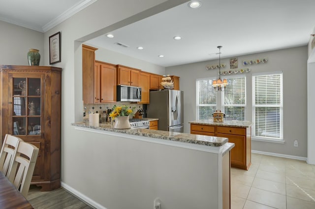 kitchen featuring decorative light fixtures, light stone countertops, kitchen peninsula, and appliances with stainless steel finishes