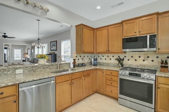 kitchen featuring sink, light tile patterned floors, stainless steel appliances, light stone countertops, and decorative backsplash