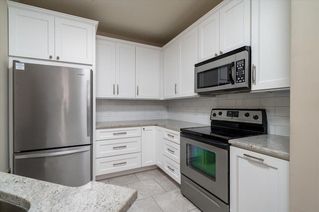 kitchen with light tile patterned flooring, stainless steel appliances, tasteful backsplash, and white cabinetry