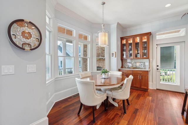 dining space featuring dark wood-style floors, baseboards, and ornamental molding