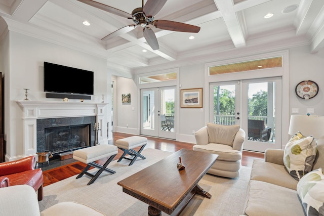 living room featuring light wood-style flooring, a fireplace, coffered ceiling, and french doors