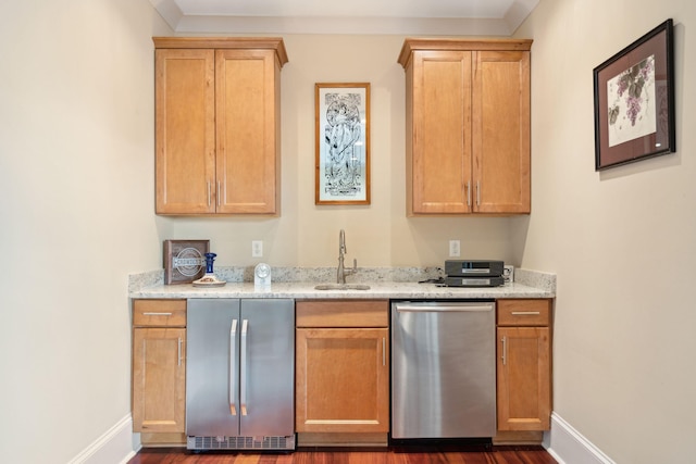 kitchen featuring stainless steel appliances, a sink, baseboards, and light stone countertops