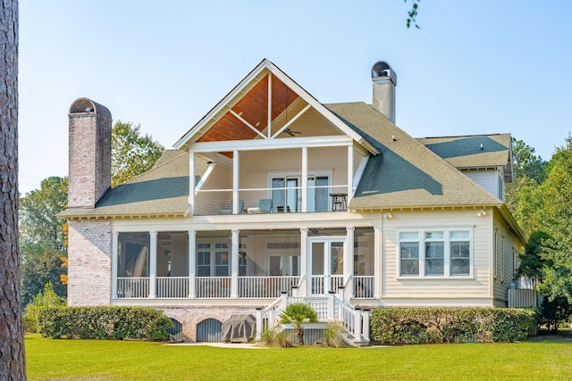 back of property with a yard, a chimney, a balcony, and a sunroom