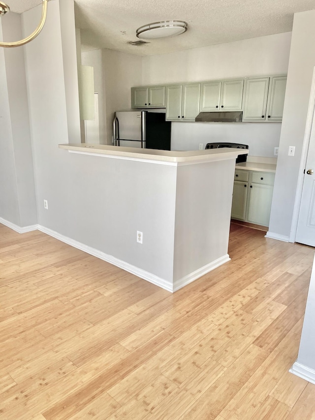 kitchen featuring stainless steel fridge, light hardwood / wood-style flooring, and a textured ceiling