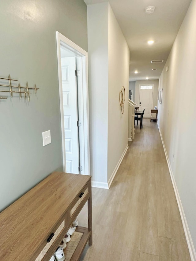 hall featuring light wood-type flooring and baseboards