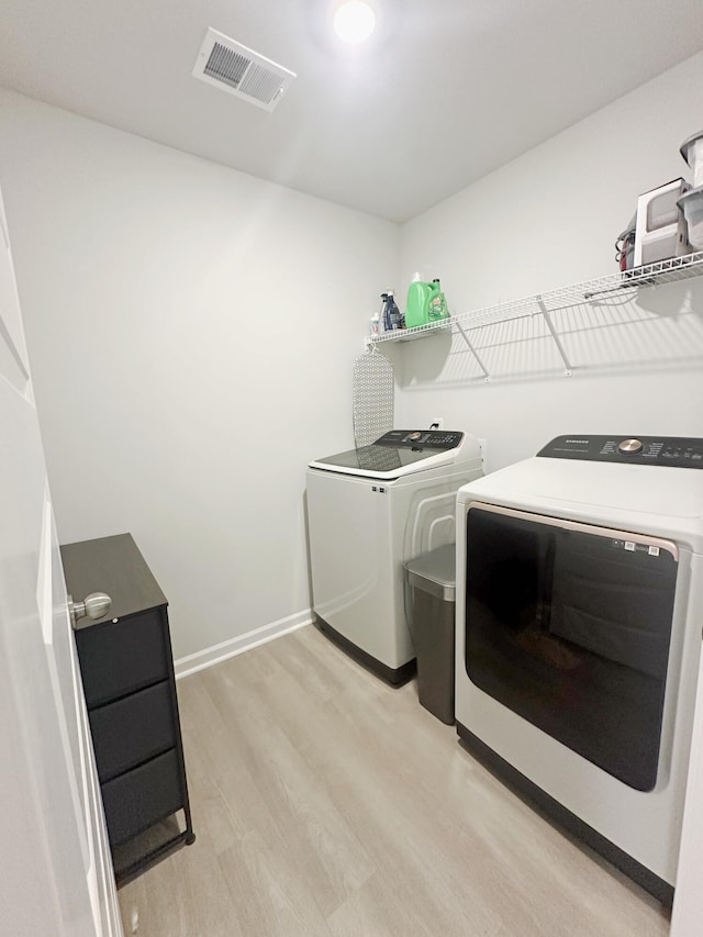 laundry room with separate washer and dryer and light hardwood / wood-style floors