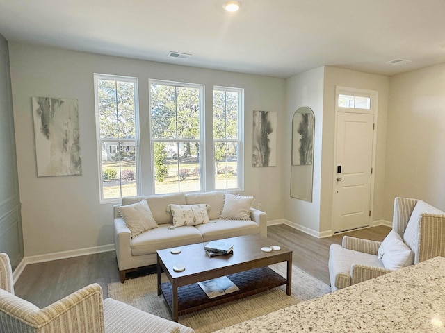 living room with baseboards, visible vents, and wood finished floors