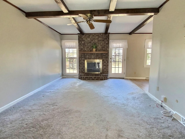 unfurnished living room featuring a brick fireplace, beam ceiling, and plenty of natural light