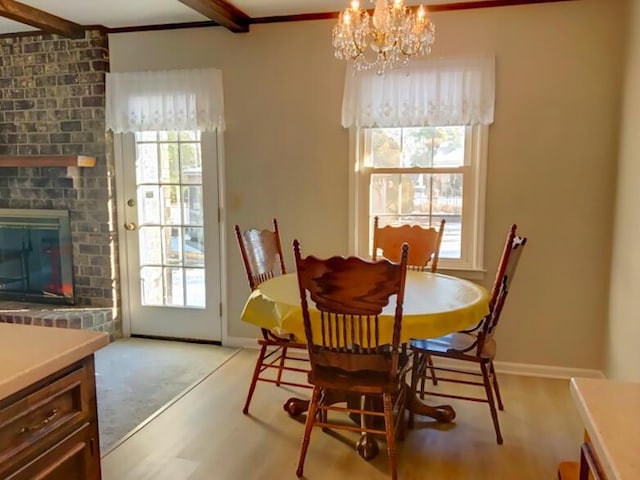 dining area with beam ceiling, a chandelier, and a brick fireplace