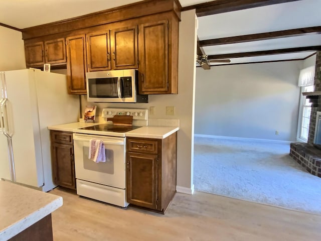 kitchen featuring a brick fireplace, light hardwood / wood-style flooring, ceiling fan, beamed ceiling, and white appliances