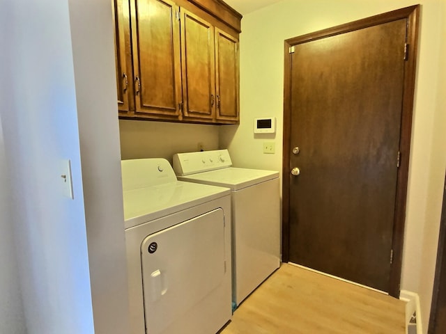 laundry room with cabinets, washing machine and clothes dryer, and light hardwood / wood-style flooring