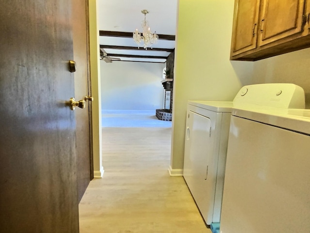 clothes washing area featuring cabinets, a notable chandelier, light hardwood / wood-style flooring, and washing machine and clothes dryer