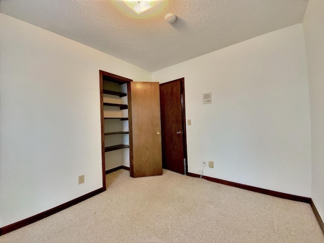 unfurnished bedroom with light colored carpet and a textured ceiling