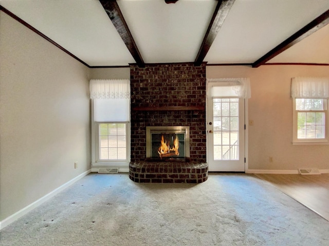 unfurnished living room with beam ceiling, plenty of natural light, carpet floors, and a fireplace