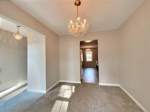 carpeted empty room featuring a notable chandelier