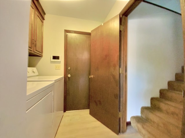 laundry room with cabinets, light wood-type flooring, and washer and clothes dryer