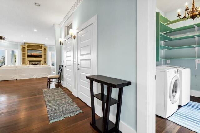 clothes washing area featuring dark hardwood / wood-style floors, an inviting chandelier, washer and clothes dryer, and crown molding