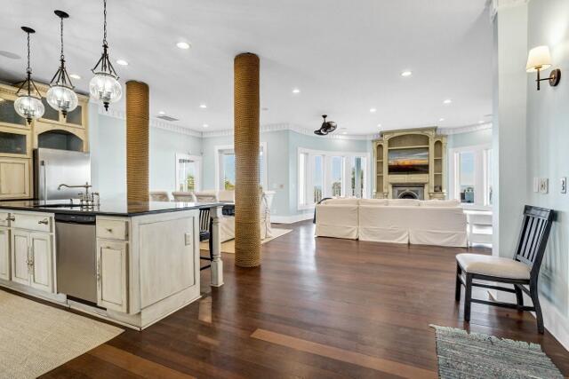 kitchen featuring hanging light fixtures, stainless steel appliances, dark hardwood / wood-style flooring, a breakfast bar, and ornamental molding