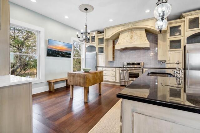 kitchen featuring appliances with stainless steel finishes, custom range hood, sink, pendant lighting, and cream cabinetry