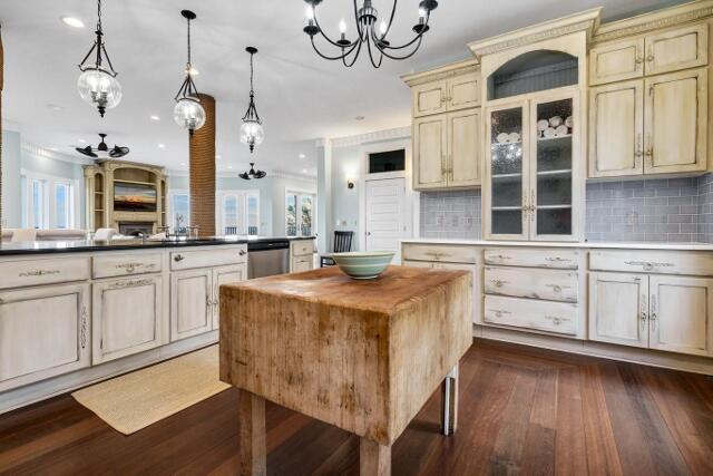 kitchen with cream cabinets, stainless steel dishwasher, tasteful backsplash, a kitchen island, and dark hardwood / wood-style flooring