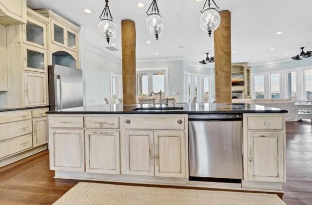 kitchen with appliances with stainless steel finishes, ornamental molding, sink, cream cabinetry, and hanging light fixtures