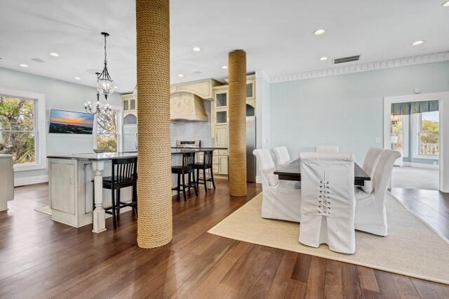 dining space with ornate columns, plenty of natural light, dark wood-type flooring, and ornamental molding