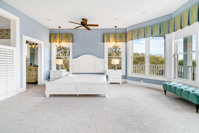 bedroom featuring light carpet, connected bathroom, and ceiling fan with notable chandelier