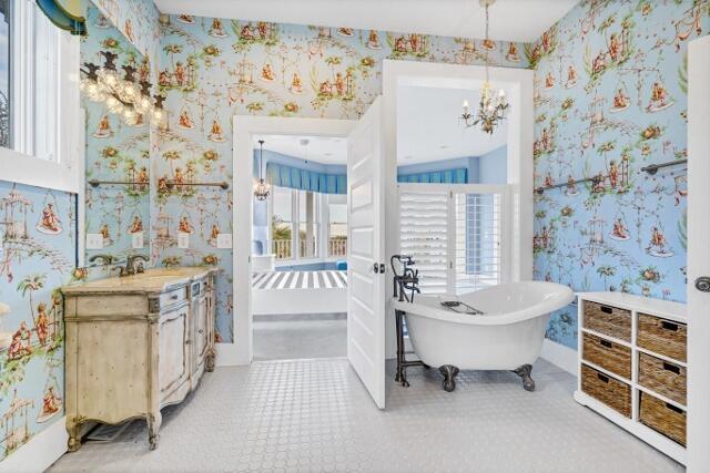 bathroom featuring a notable chandelier, vanity, and a washtub