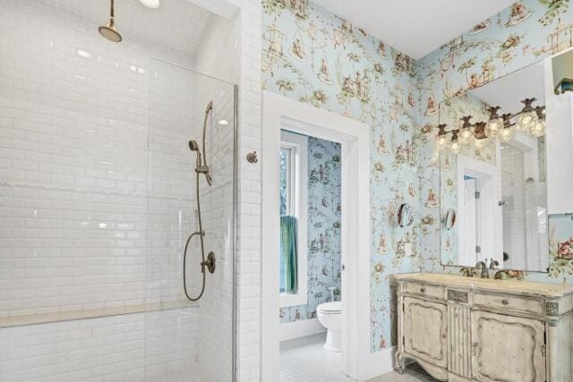 bathroom with toilet, vanity, and tiled shower