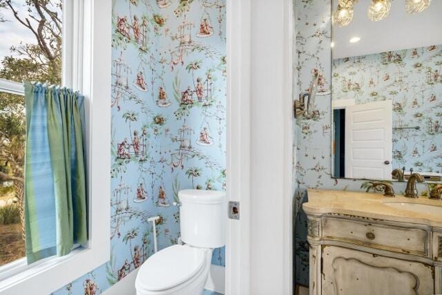 bathroom with plenty of natural light, vanity, a chandelier, and toilet