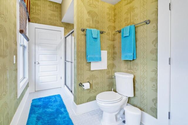 bathroom featuring a shower with shower door and toilet