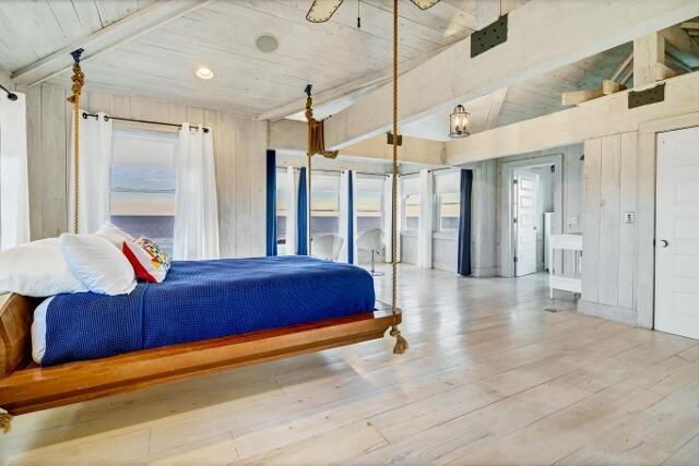 bedroom featuring vaulted ceiling with beams, wooden ceiling, and light wood-type flooring