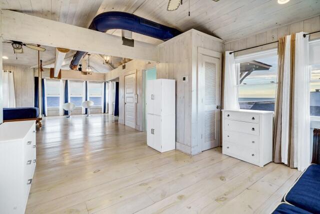 kitchen with light hardwood / wood-style floors, white cabinetry, lofted ceiling, and wood walls